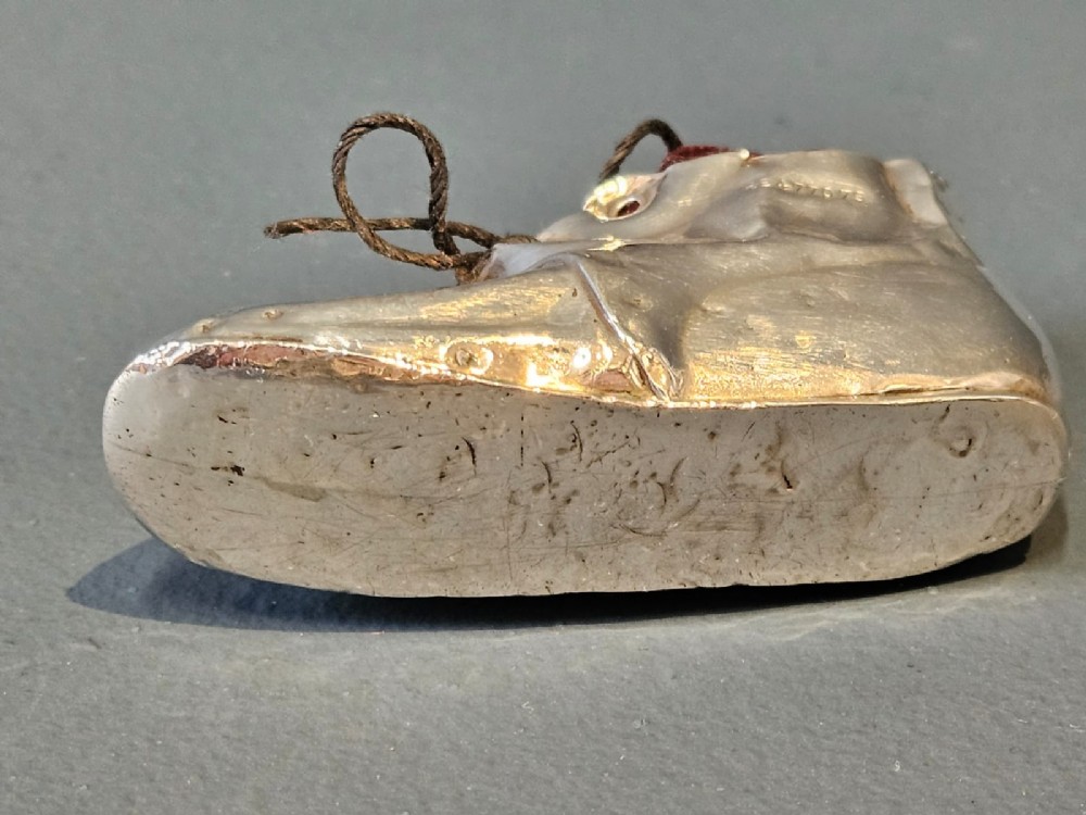 An Edwardian sterling silver pin cushion crafted in the form of a childs boot with a dark red velvet cushion top and cord laces. View VI