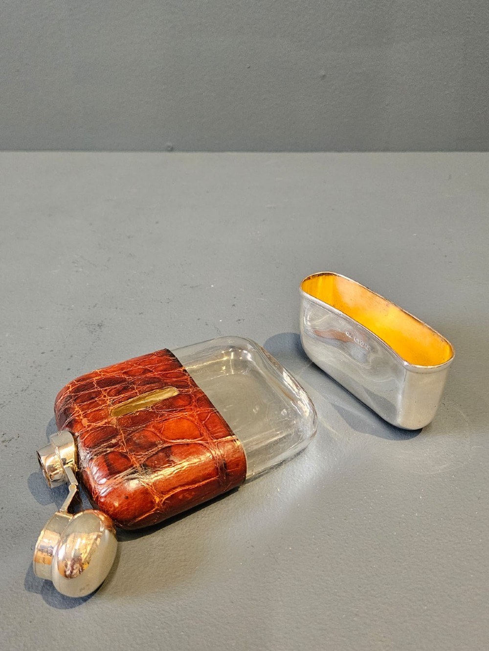 An antique silver hip flask partially encased in brown textured crocodile skin with a bayonet cap and removable base cup. View II