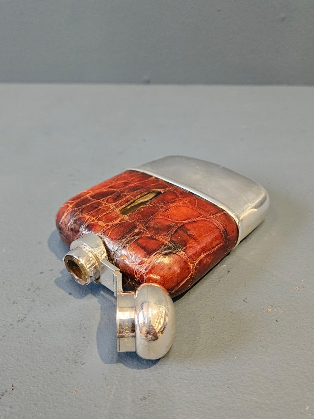 An antique silver hip flask partially encased in brown textured crocodile skin with a bayonet cap and removable base cup. View III