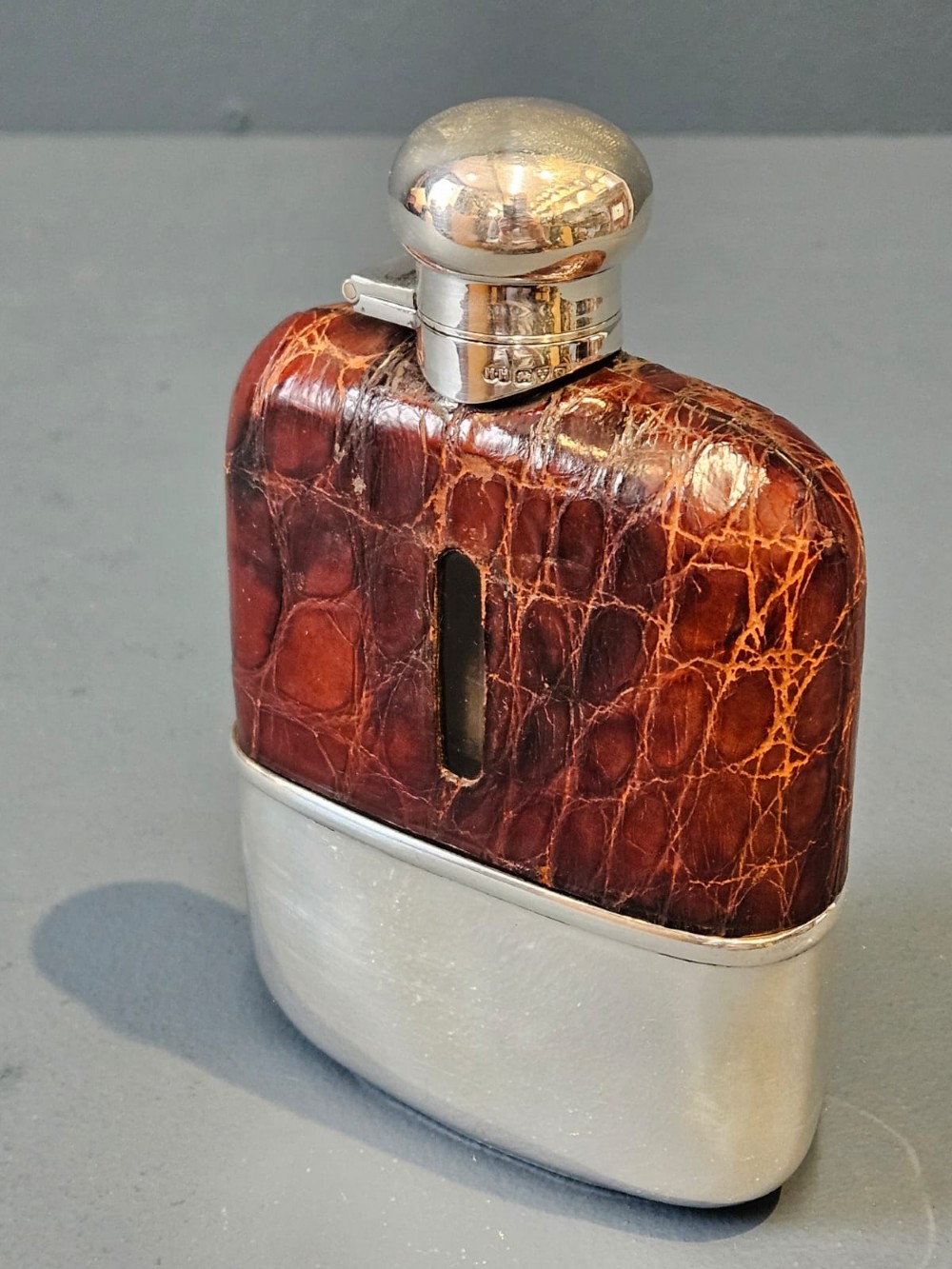 An antique silver hip flask partially encased in brown textured crocodile skin with a bayonet cap and removable base cup. View VI