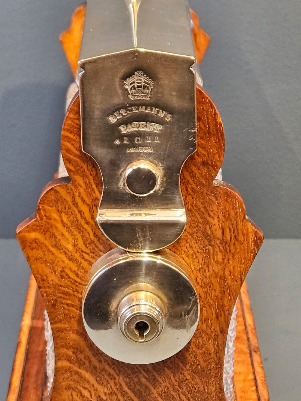 A Victorian oak three-bottle tantalus featuring a wooden frame with silver-plated mounts and three cut-glass square decanters with round faceted stoppers. View VII