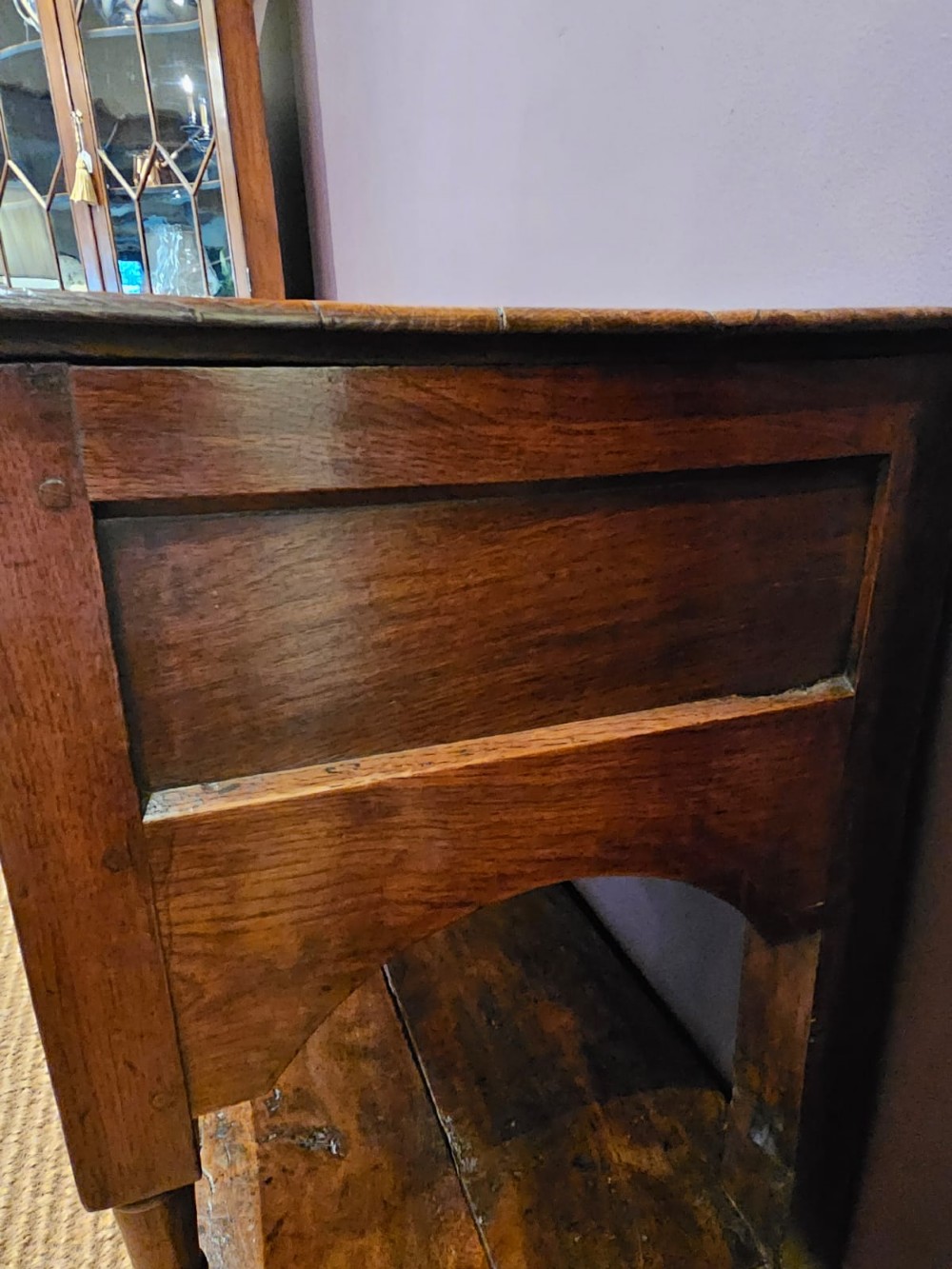 A George III oak open pot board dresser base featuring three drawers with brass drop handles, a shaped arched apron, and turned legs. View IV