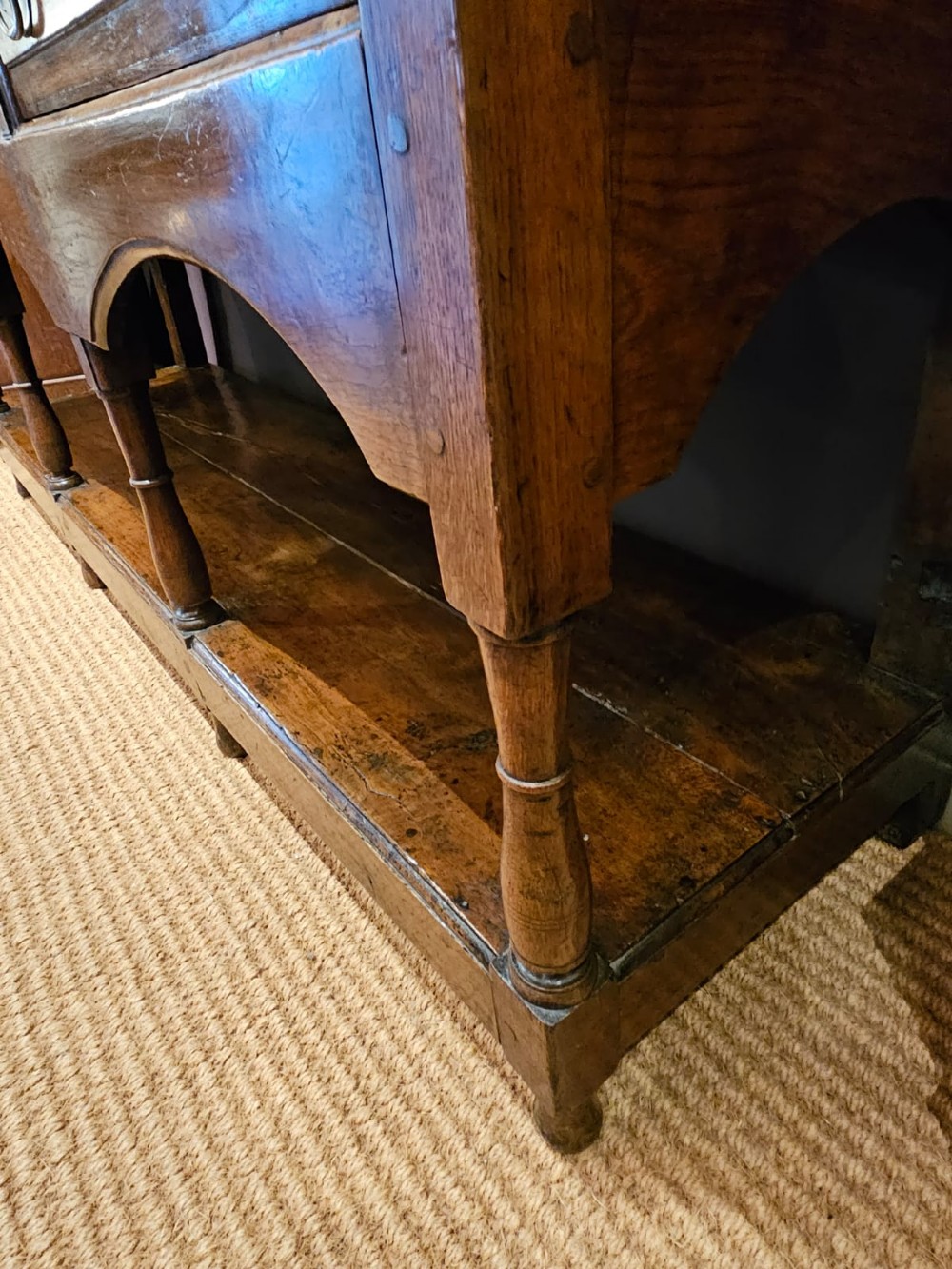 A George III oak open pot board dresser base featuring three drawers with brass drop handles, a shaped arched apron, and turned legs. View VIII
