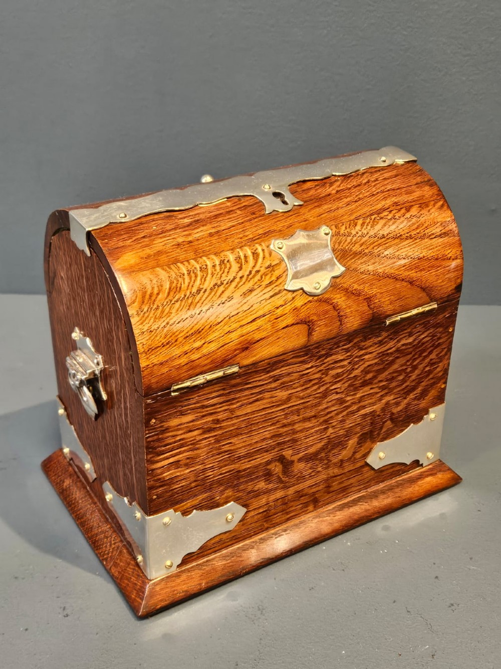A Victorian domed oak tea caddy featuring silver-plated corner mounts, an escutcheon, and side carrying handles.