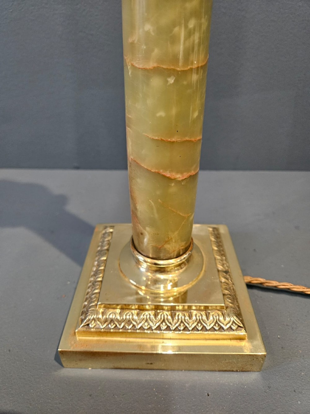 A late Victorian table lamp featuring a brass Corinthian capital, a cylindrical green marble shaft, and a square stepped brass base. View II