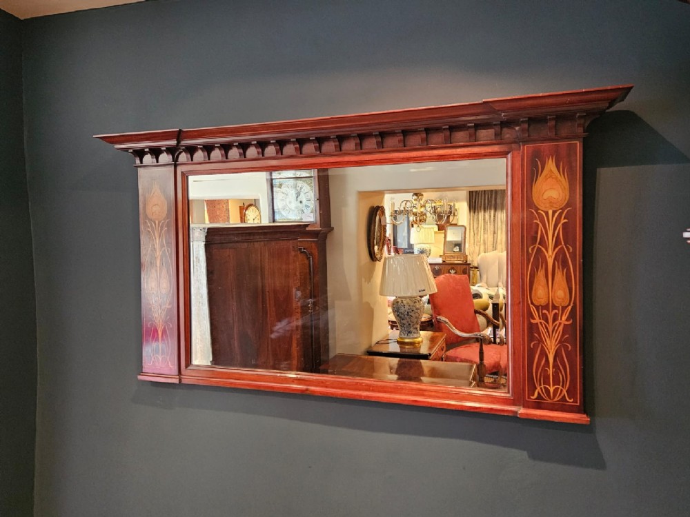 An Edwardian rectangular mahogany wall mirror featuring decorative marquetry side panels with stylised floral motifs and a corbelled top cornice. View II