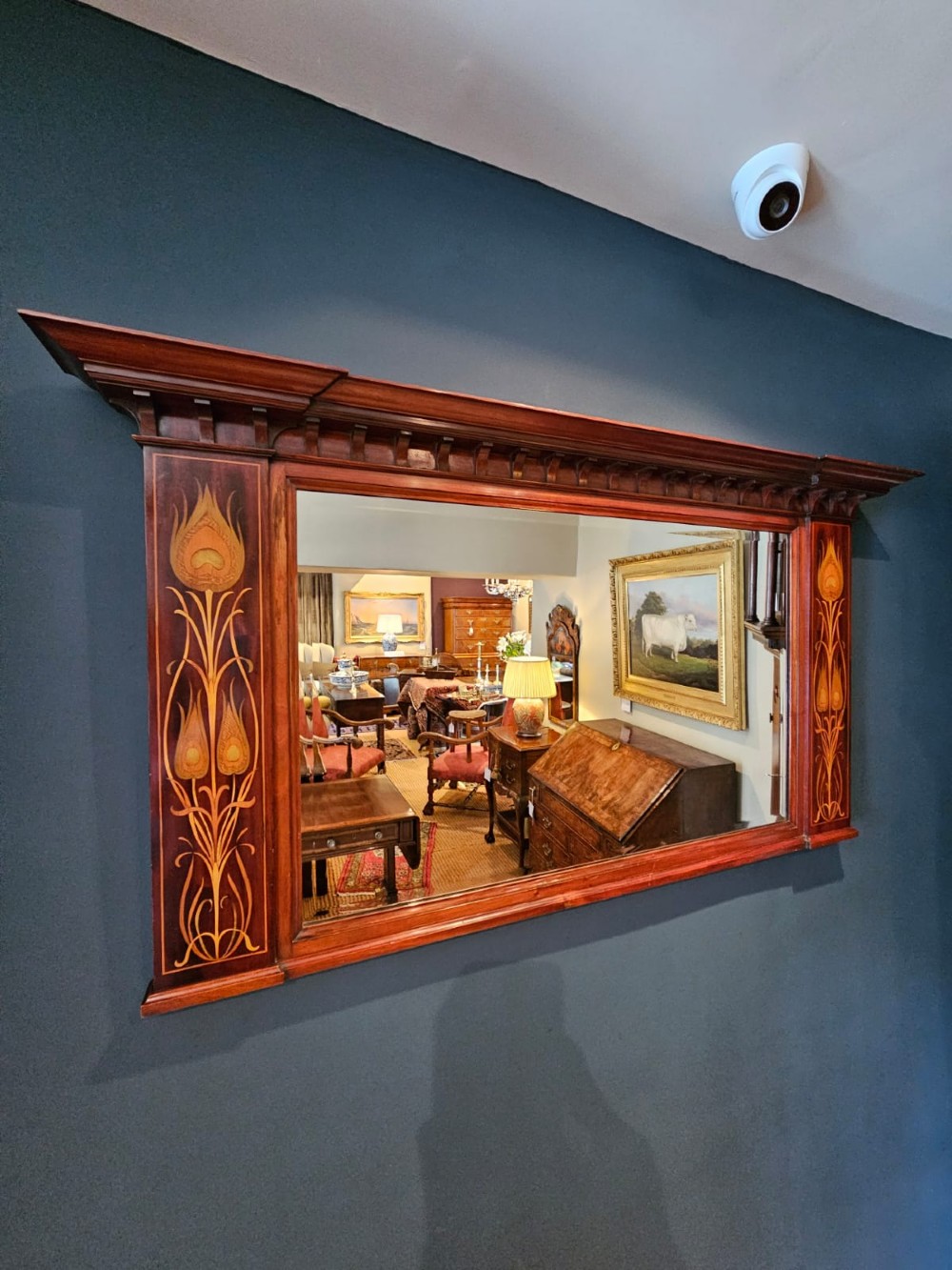 An Edwardian rectangular mahogany wall mirror featuring decorative marquetry side panels with stylised floral motifs and a corbelled top cornice. View III