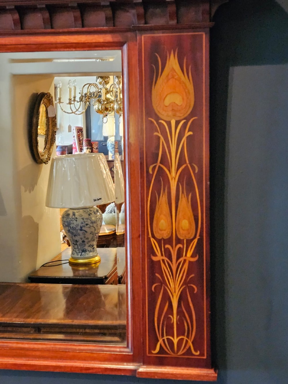 An Edwardian rectangular mahogany wall mirror featuring decorative marquetry side panels with stylised floral motifs and a corbelled top cornice. View IV