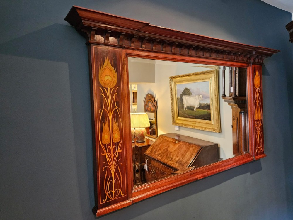 An Edwardian rectangular mahogany wall mirror featuring decorative marquetry side panels with stylised floral motifs and a corbelled top cornice. View V