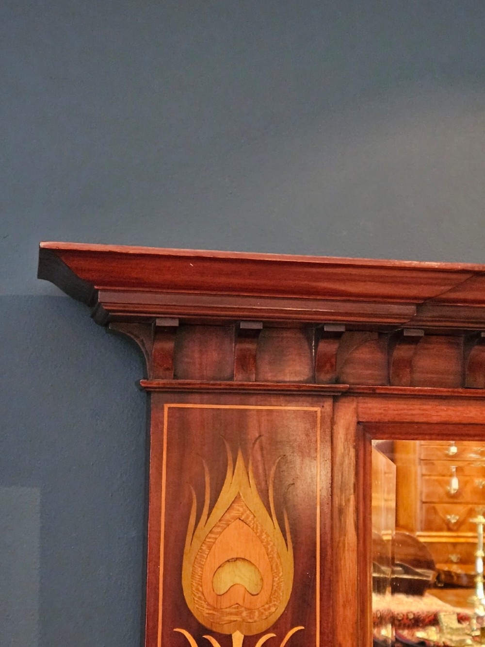 An Edwardian rectangular mahogany wall mirror featuring decorative marquetry side panels with stylised floral motifs and a corbelled top cornice. View VI