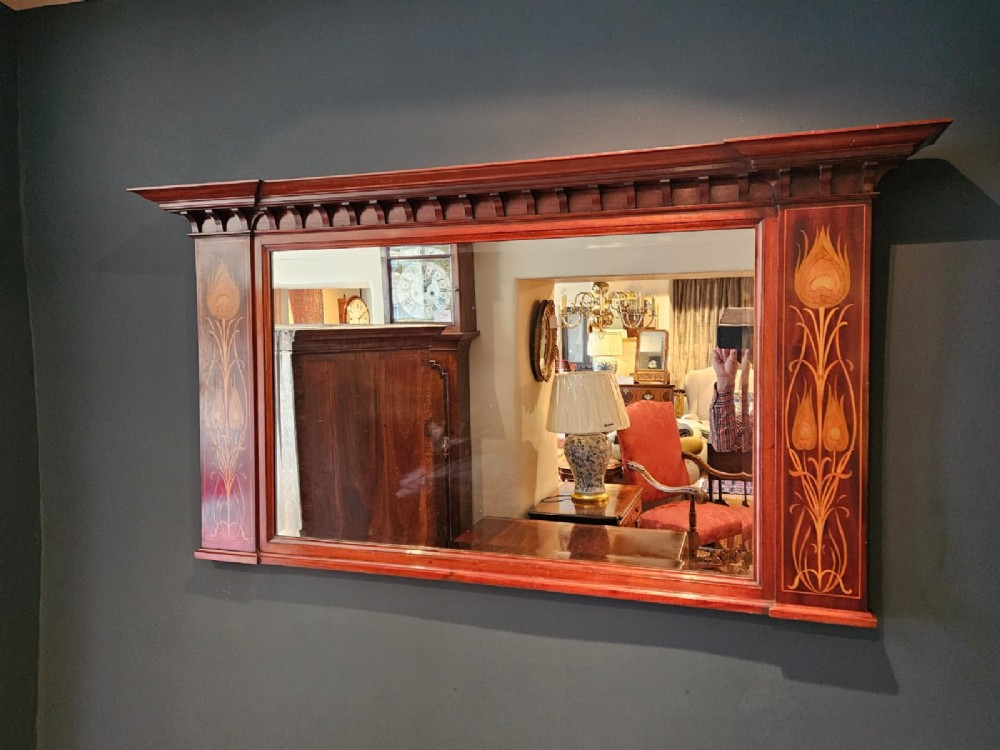 An Edwardian rectangular mahogany wall mirror featuring decorative marquetry side panels with stylised floral motifs and a corbelled top cornice. View VII