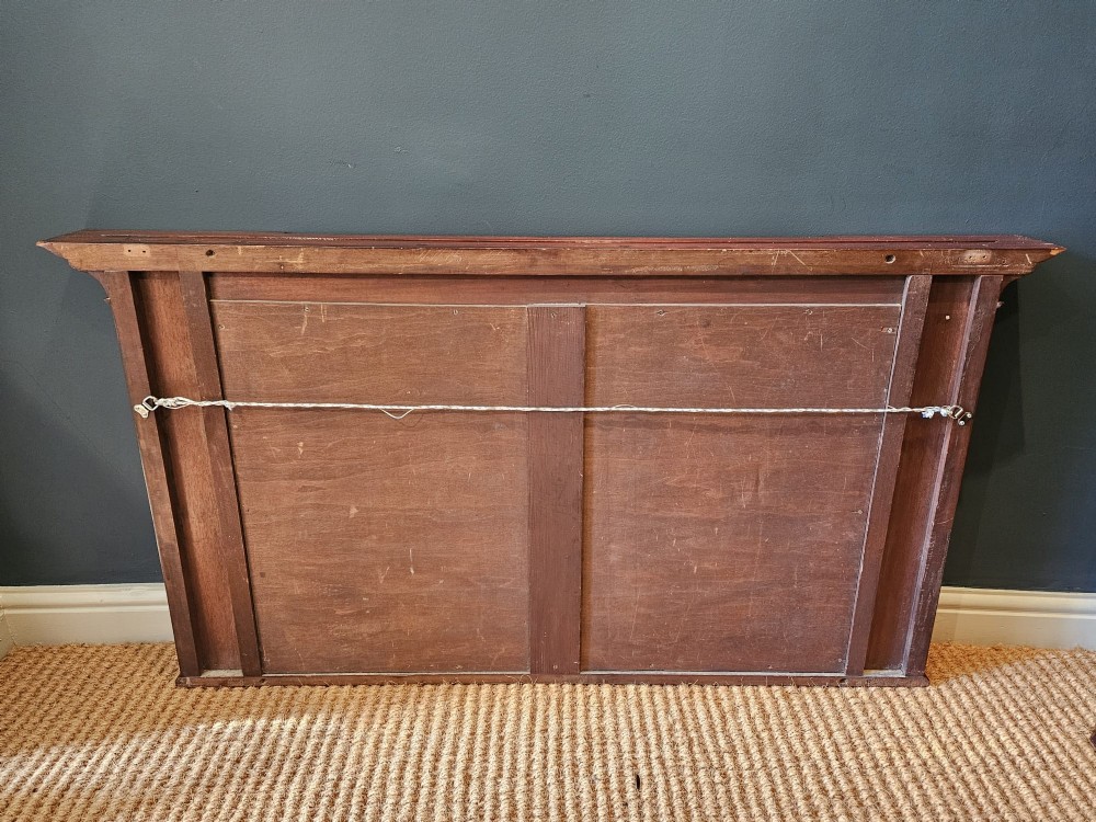An Edwardian rectangular mahogany wall mirror featuring decorative marquetry side panels with stylised floral motifs and a corbelled top cornice. View XI