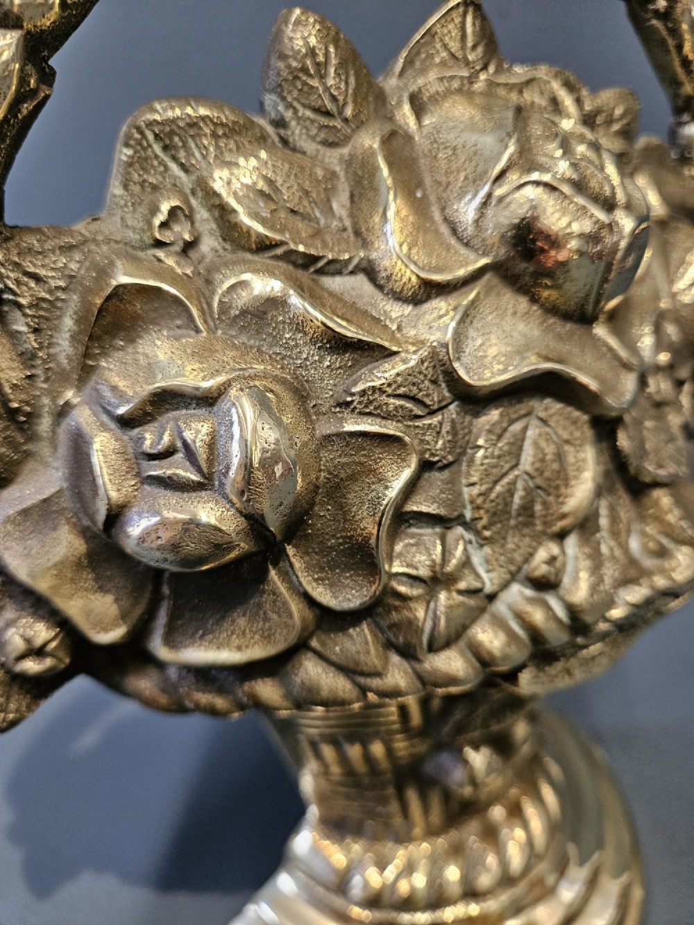 A Victorian cast brass doorstop featuring a detailed relief of roses inside a basket with an integrated loop handle. View III