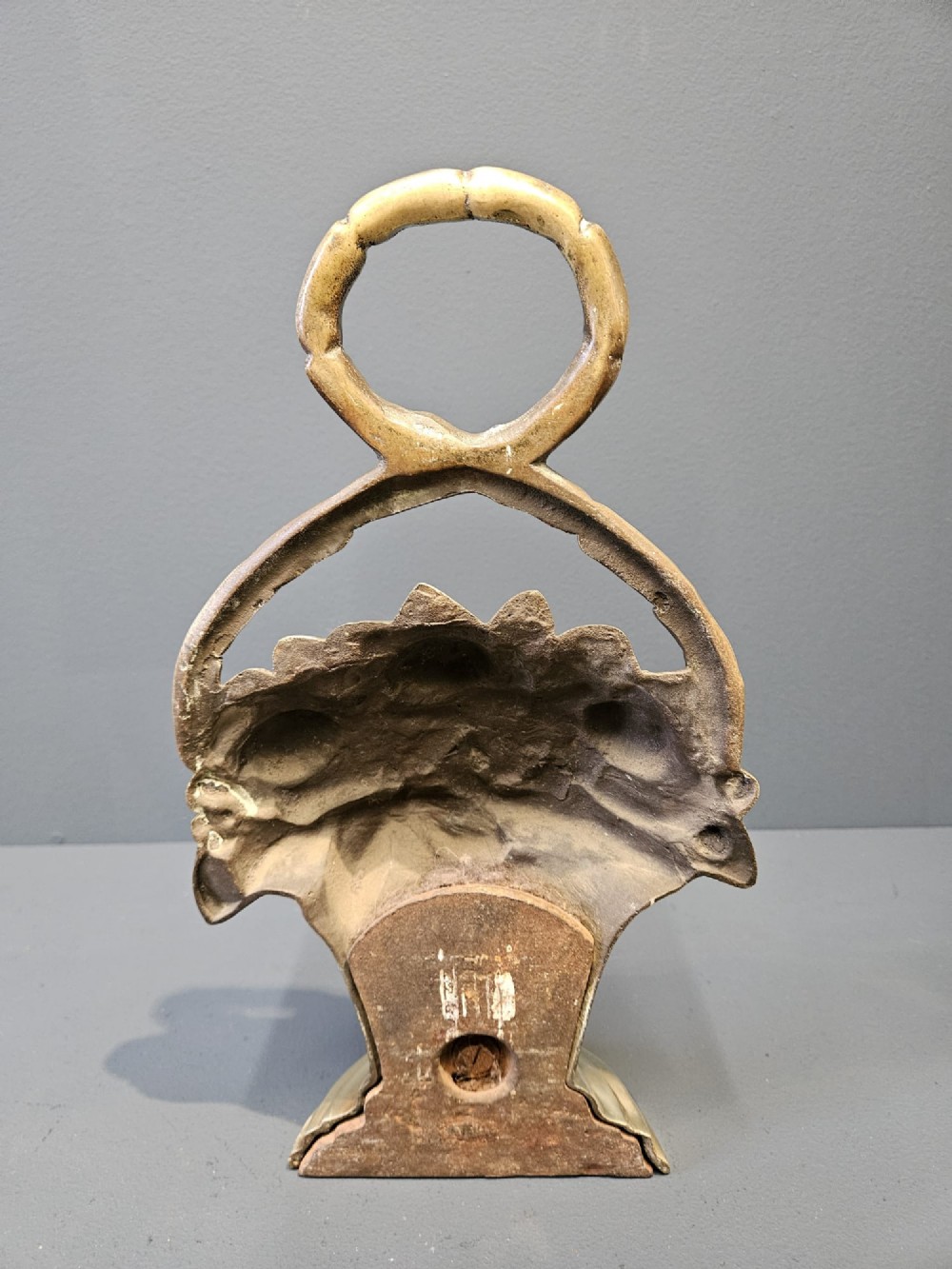 A Victorian cast brass doorstop featuring a detailed relief of roses inside a basket with an integrated loop handle. View IV