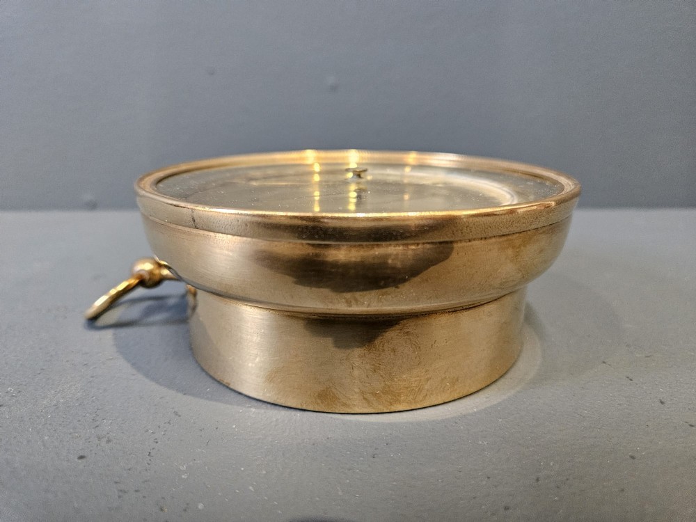 A circular Victorian brass aneroid barometer featuring an engraved face with weather markings, an integrated thermometer, and a top hanging ring. View II