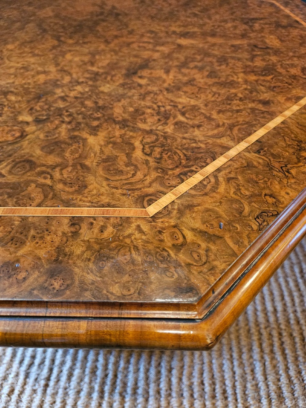 An octagonal burr walnut low coffee table featuring light wood stringing inlay, four barley twist support legs, and a central turned column on a quadruped base. View IV