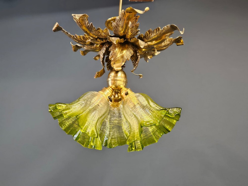 Victorian ceiling light featuring cast brass leaf motifs around the ceiling mount above fluted green glass shades.