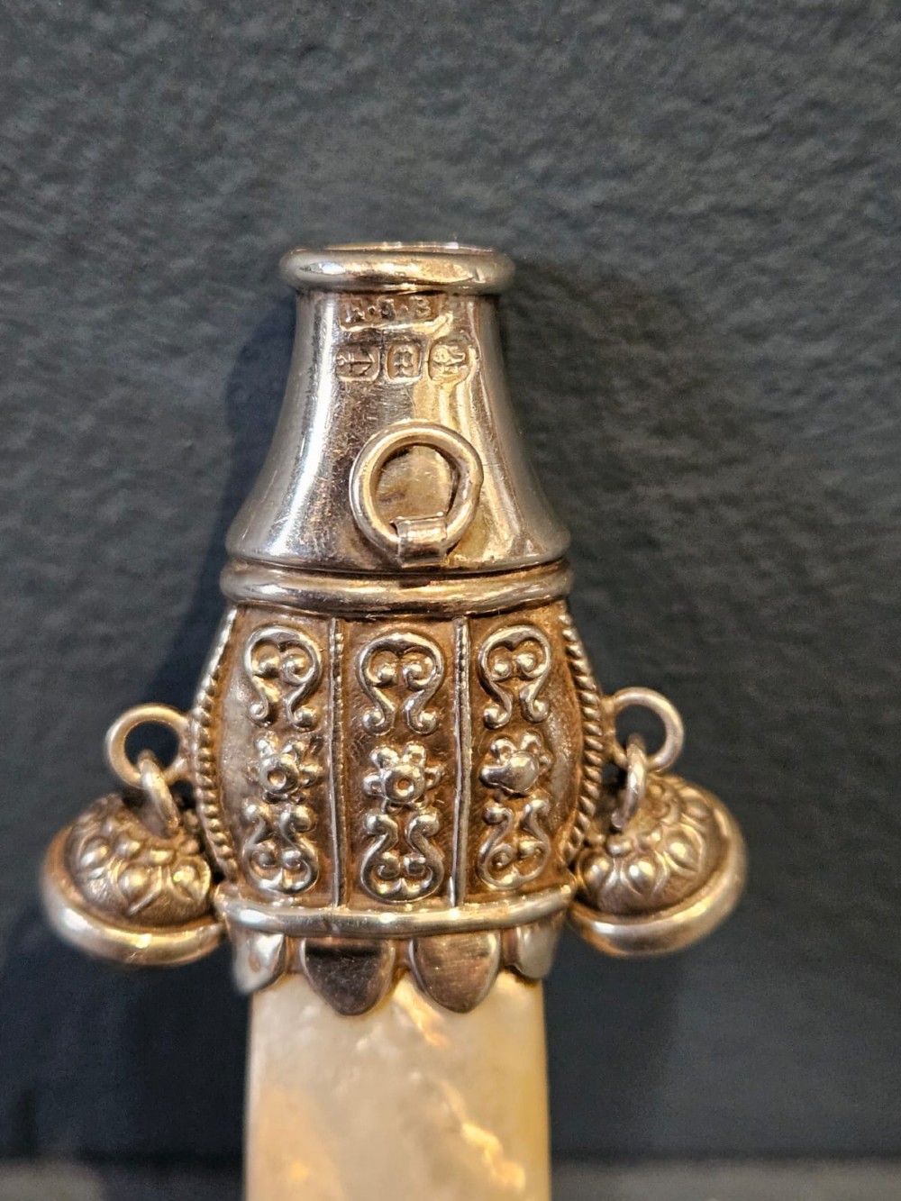 A Victorian silver and mother-of-pearl baby teether featuring a whistle end, repousse silver scrollwork, and a small hanging bell. View III