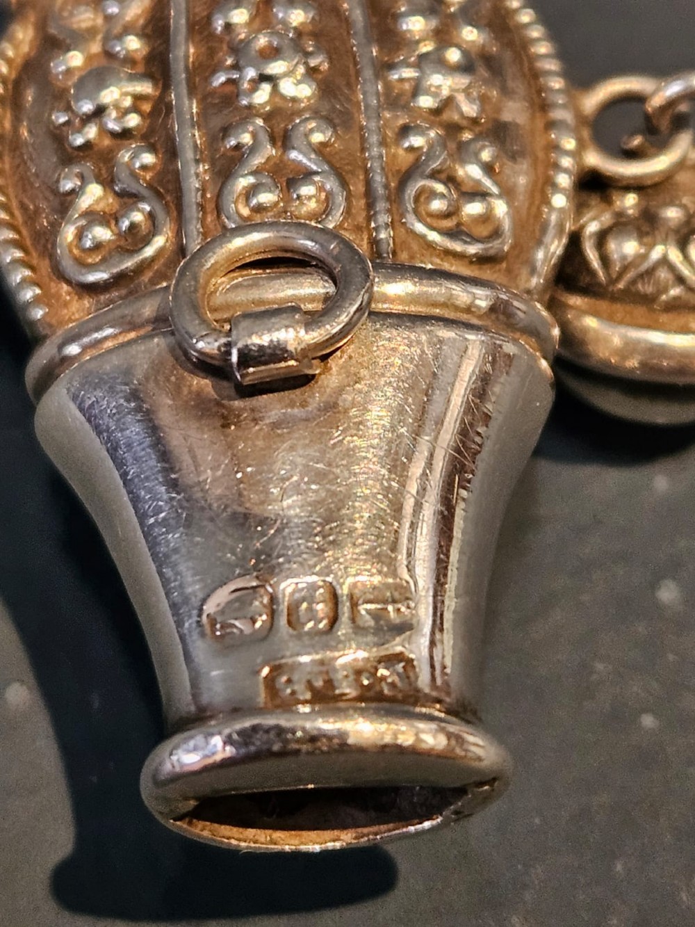 A Victorian silver and mother-of-pearl baby teether featuring a whistle end, repousse silver scrollwork, and a small hanging bell. View VI