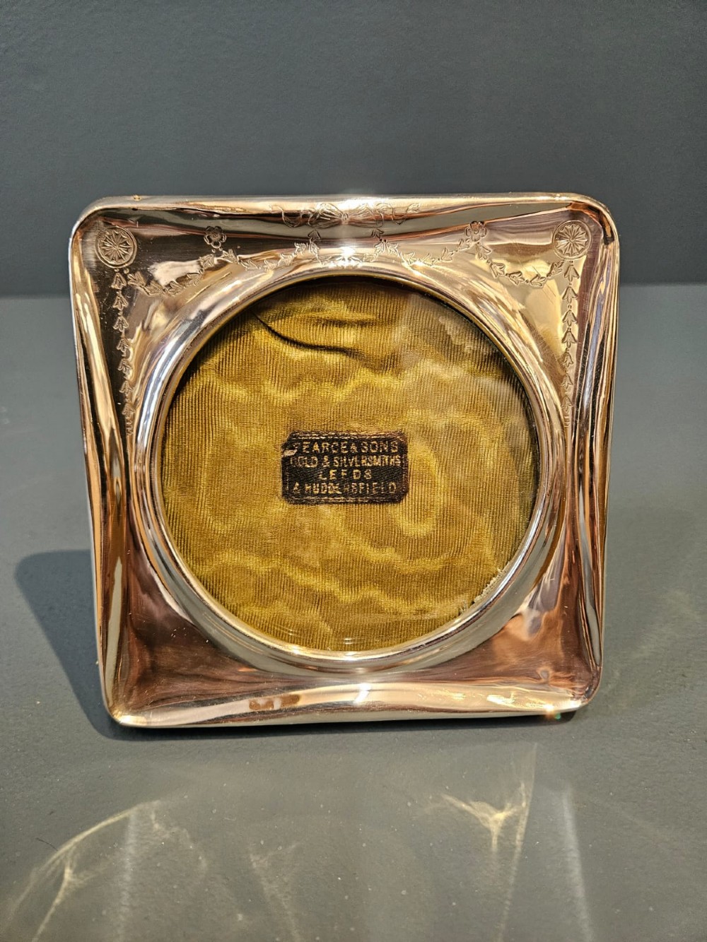 Square Edwardian silver photo frame with decorative engraved swags and a circular central window. View II