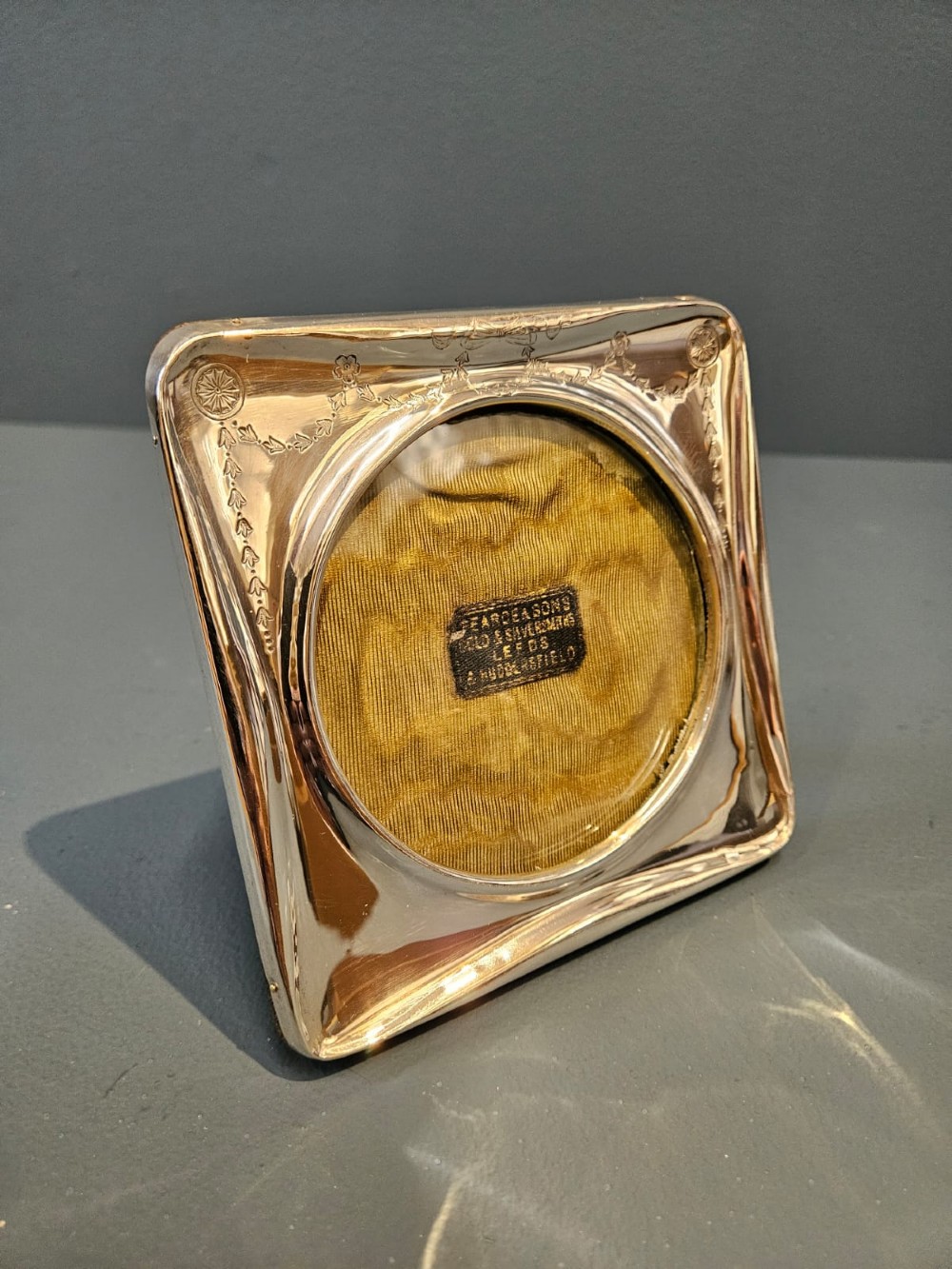 Square Edwardian silver photo frame with decorative engraved swags and a circular central window. View IV