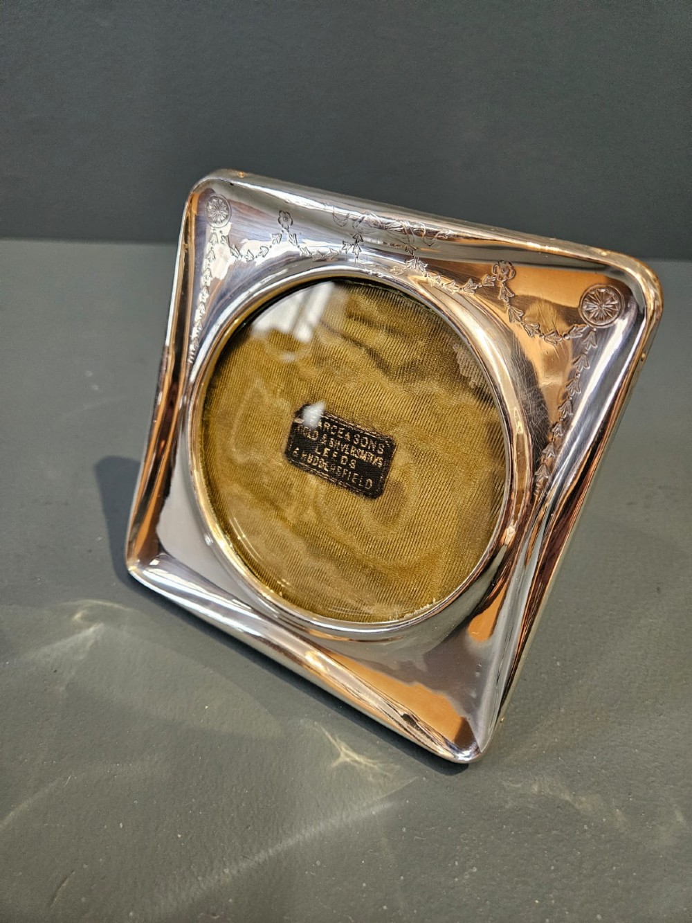 Square Edwardian silver photo frame with decorative engraved swags and a circular central window. View V