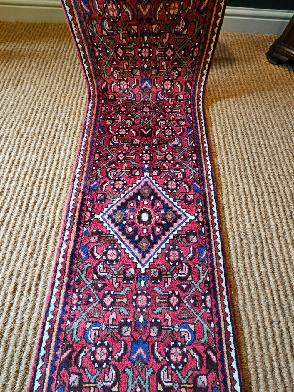 An extra-long wool hallway runner rug featuring intricate Persian geometric and floral patterns in deep red, navy blue, and cream with fringed ends. View IV