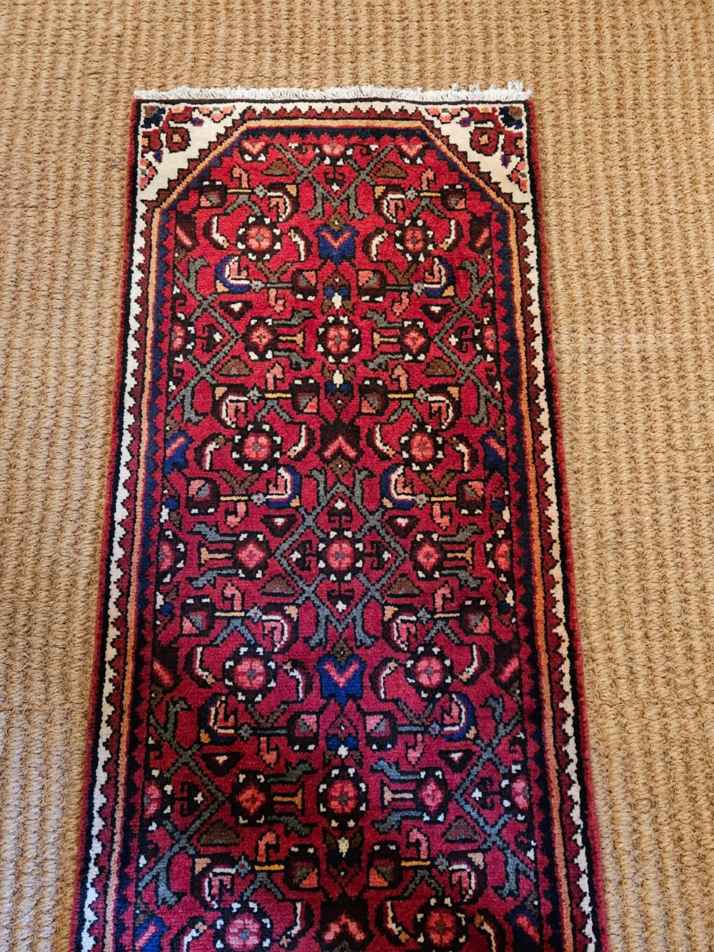 An extra-long wool hallway runner rug featuring intricate Persian geometric and floral patterns in deep red, navy blue, and cream with fringed ends. View V