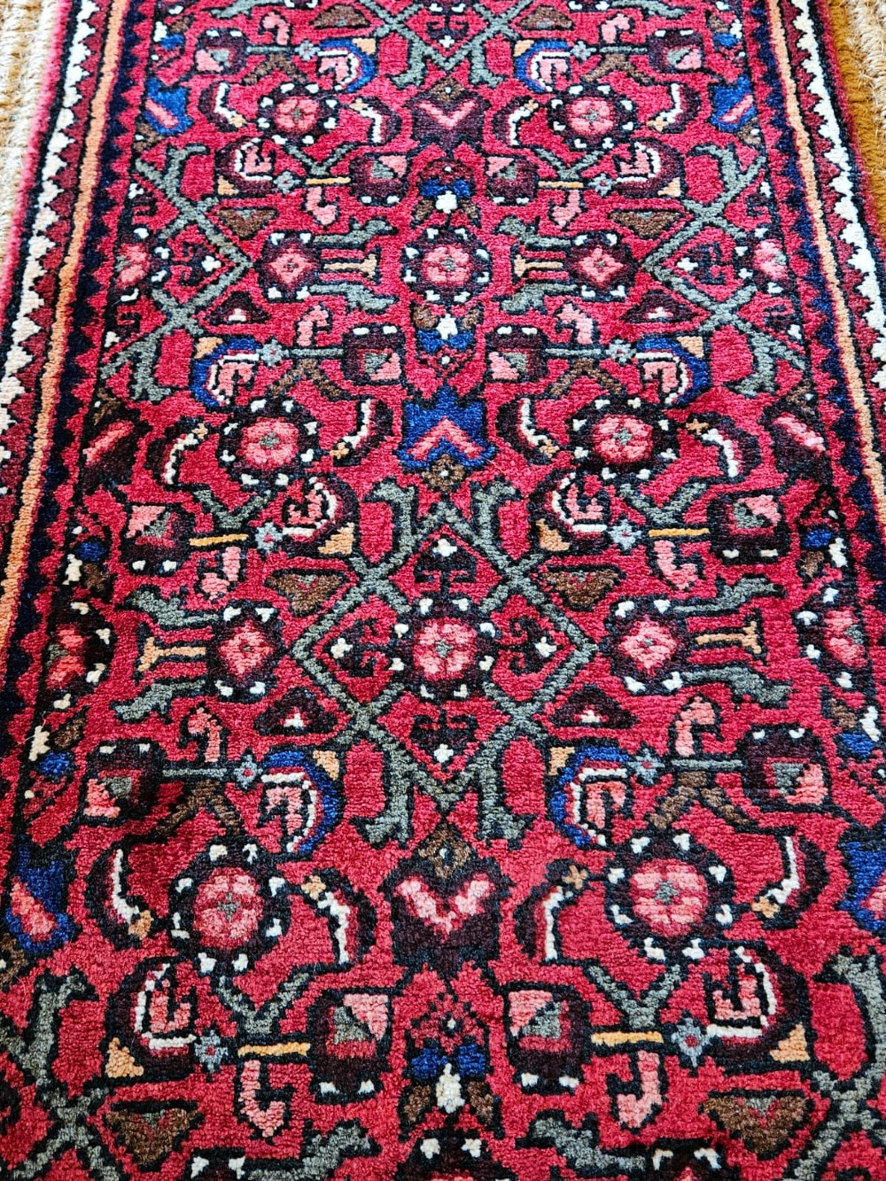 An extra-long wool hallway runner rug featuring intricate Persian geometric and floral patterns in deep red, navy blue, and cream with fringed ends. View VII