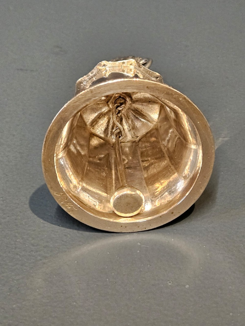 A Victorian silver table bell featuring a fruit basket finial, dual handles, a faceted body, and an embossed rim. View V