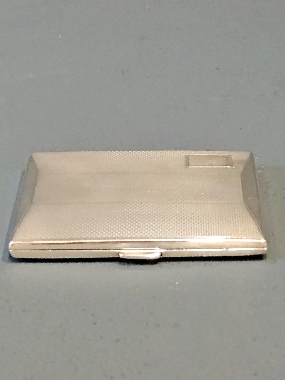 A rectangular George V sterling silver cheroot case with a subtle engine-turned geometric pattern and a blank rectangular corner cartouche.