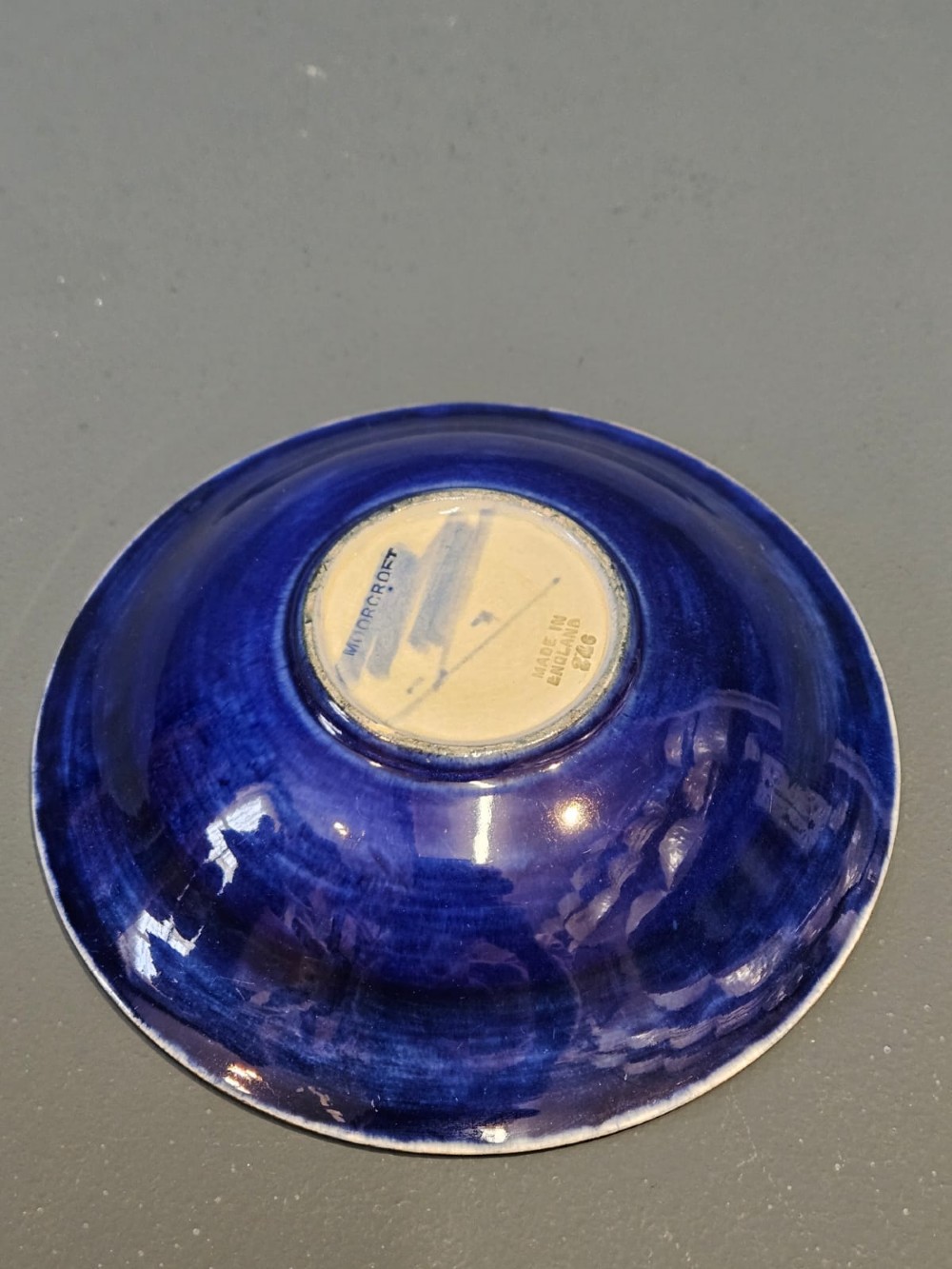 A circular shallow earthenware bowl decorated with hand-painted tubelined pomegranate fruits and dark berries over an ochre-tinted ground. View VI