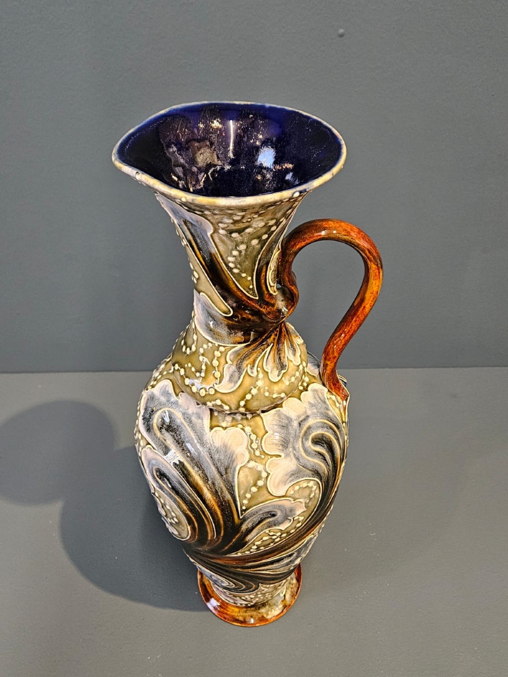 A tall Victorian Doulton Lambeth stoneware ewer decorated with incised leaf motifs, white beaded slipwork, an ochre handle, and a deep cobalt blue glazed interior. View III