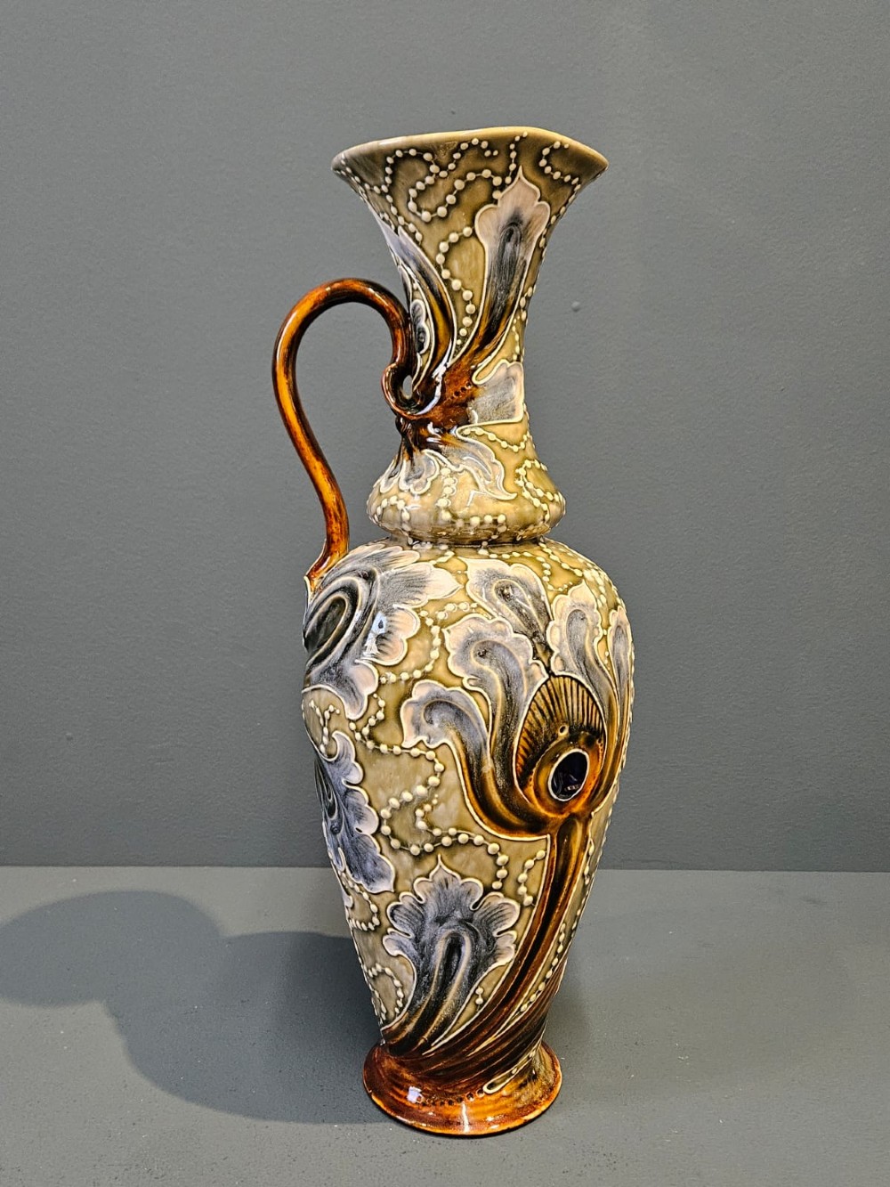 A tall Victorian Doulton Lambeth stoneware ewer decorated with incised leaf motifs, white beaded slipwork, an ochre handle, and a deep cobalt blue glazed interior. View IV