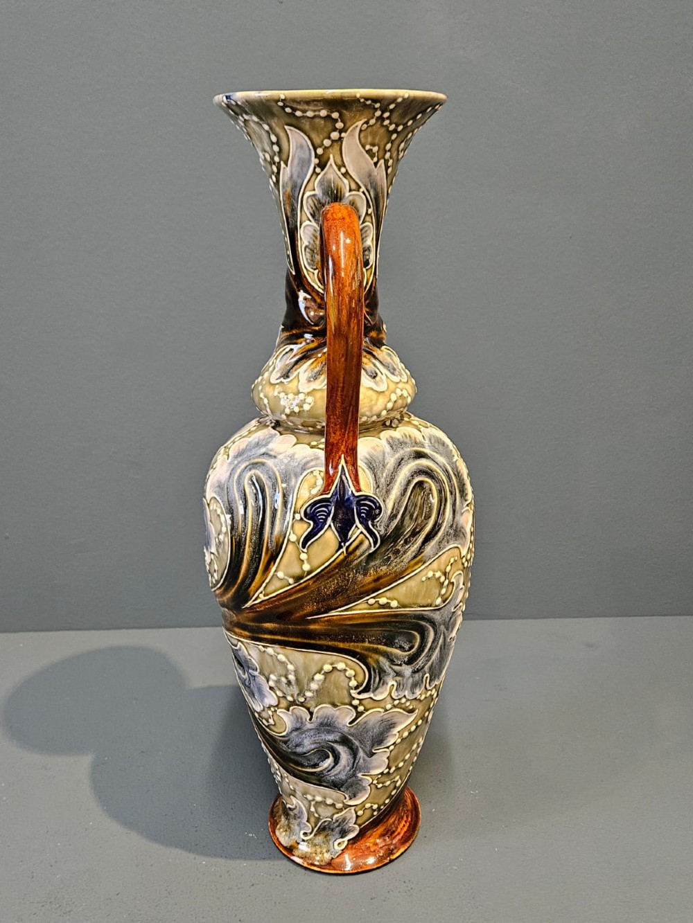 A tall Victorian Doulton Lambeth stoneware ewer decorated with incised leaf motifs, white beaded slipwork, an ochre handle, and a deep cobalt blue glazed interior. View V