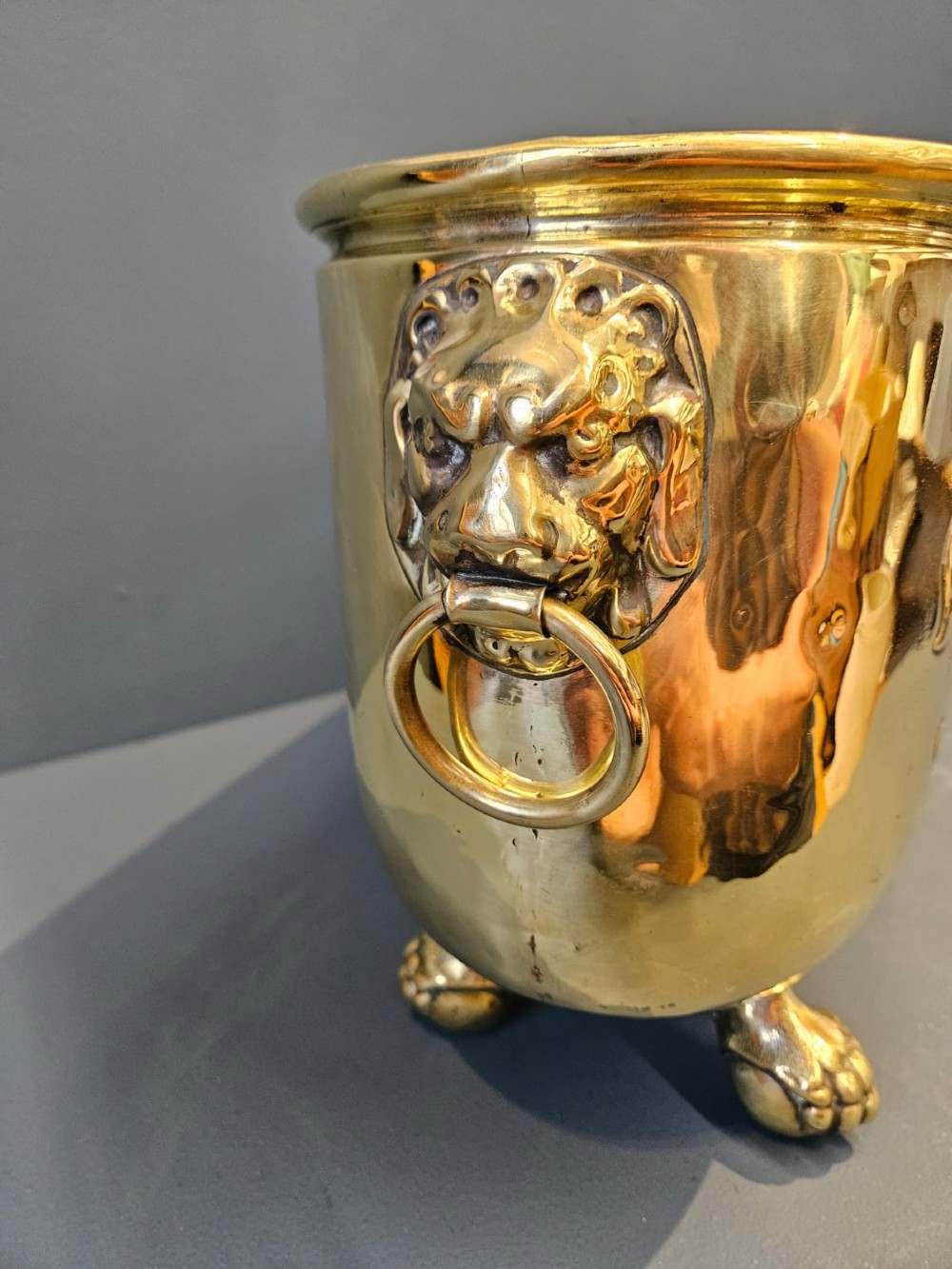 An oblong Victorian brass planter featuring an embossed armorial crest, fleur-de-lis motifs, side ring handles, and cast claw feet. View VII