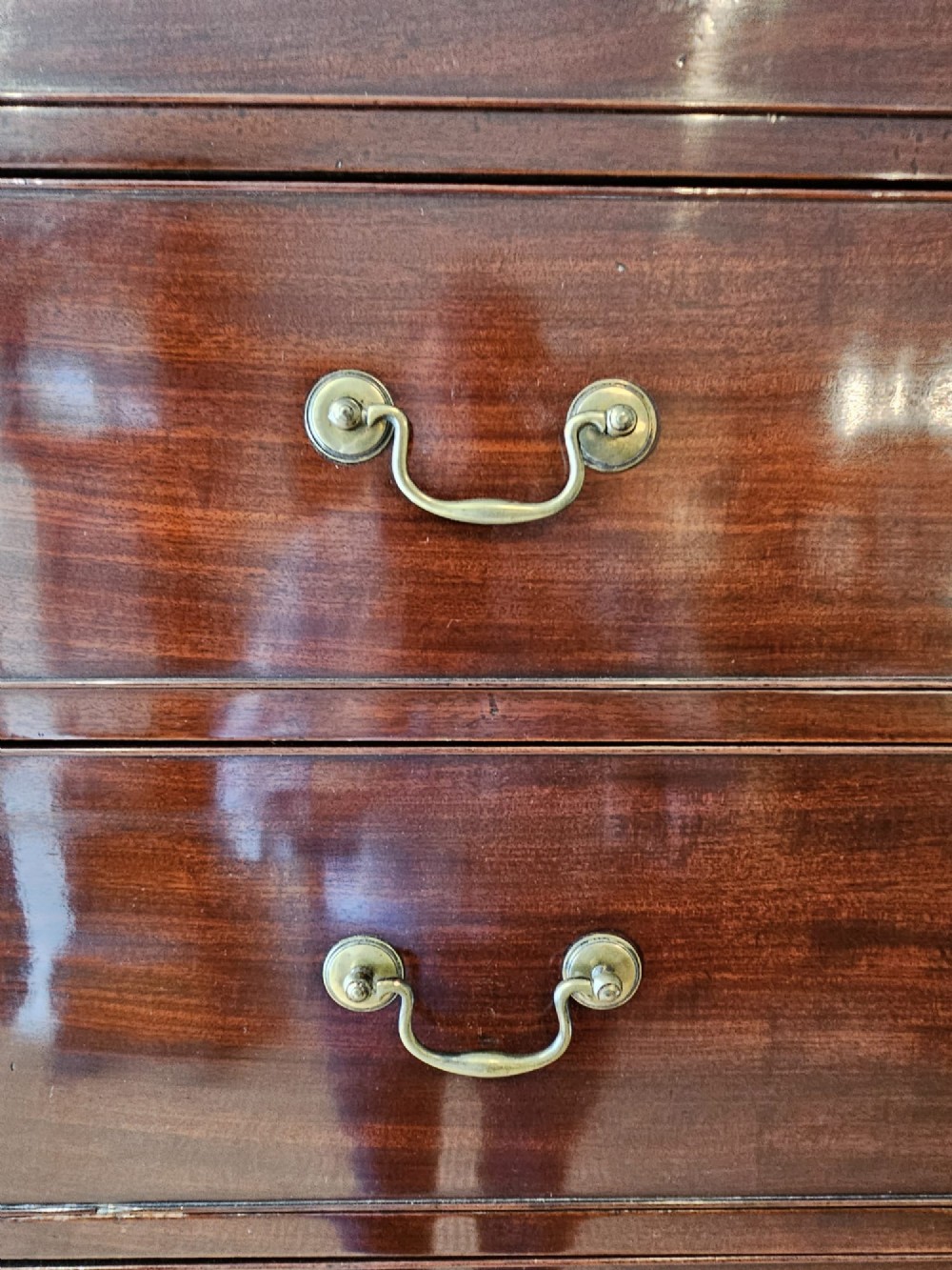 A George III mahogany chest on chest featuring two stacked drawer sections, swan-neck brass handles, dentil moulding, and bracket feet. View III