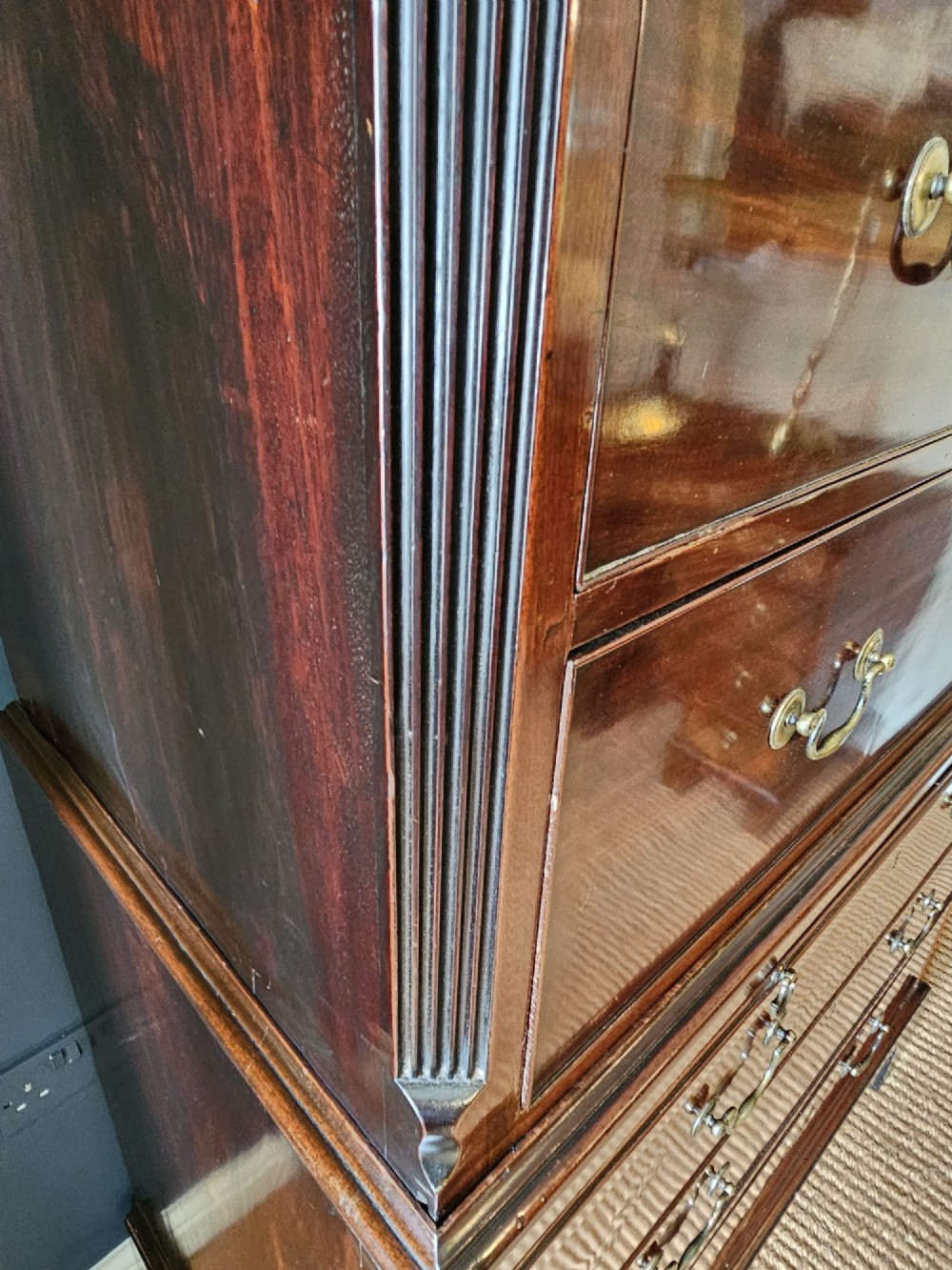 A George III mahogany chest on chest featuring two stacked drawer sections, swan-neck brass handles, dentil moulding, and bracket feet. View IV