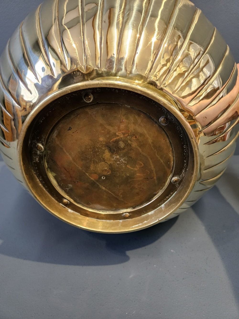 A polished Victorian brass jardiniere planter featuring embossed floral detailing around the upper band, fluted gadrooning on the lower body, and two side handles. View V