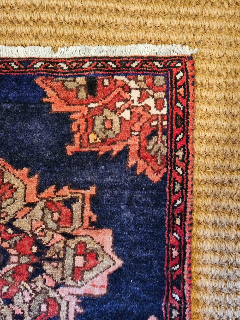 A long narrow navy blue runner rug decorated with a row of repeating geometric star medallions in terracotta and cream tones. View III