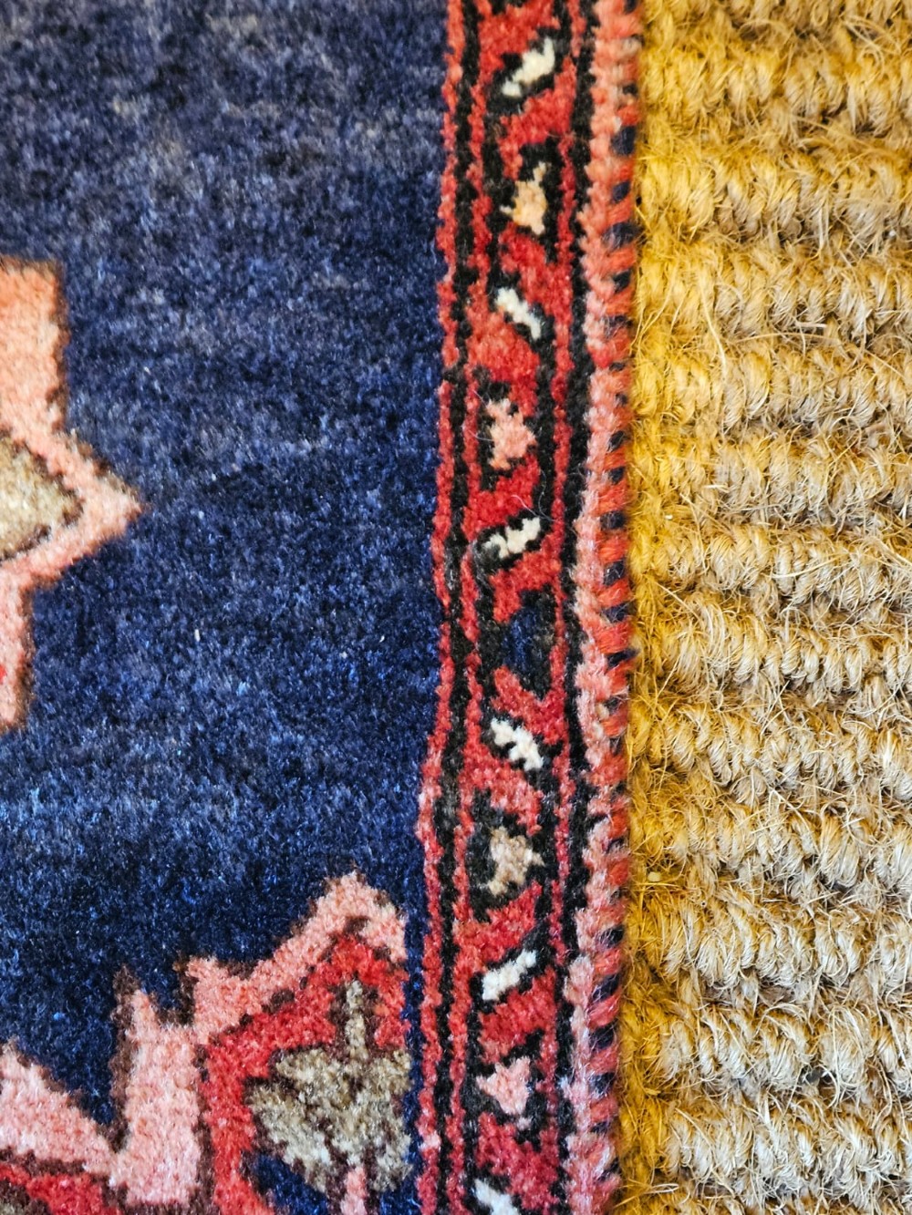 A long narrow navy blue runner rug decorated with a row of repeating geometric star medallions in terracotta and cream tones. View IV