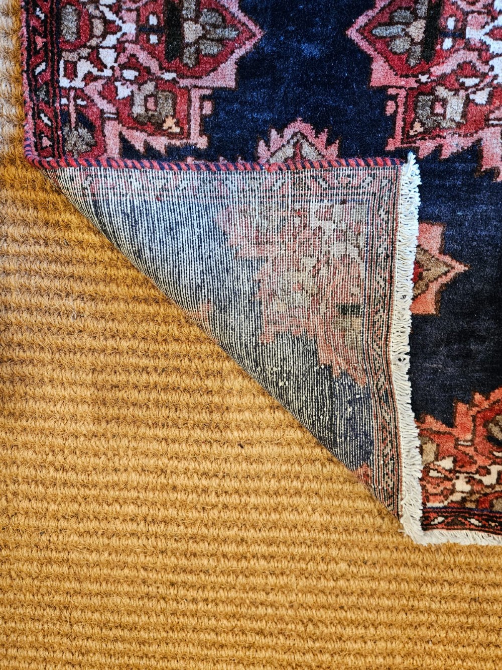 A long narrow navy blue runner rug decorated with a row of repeating geometric star medallions in terracotta and cream tones. View VI