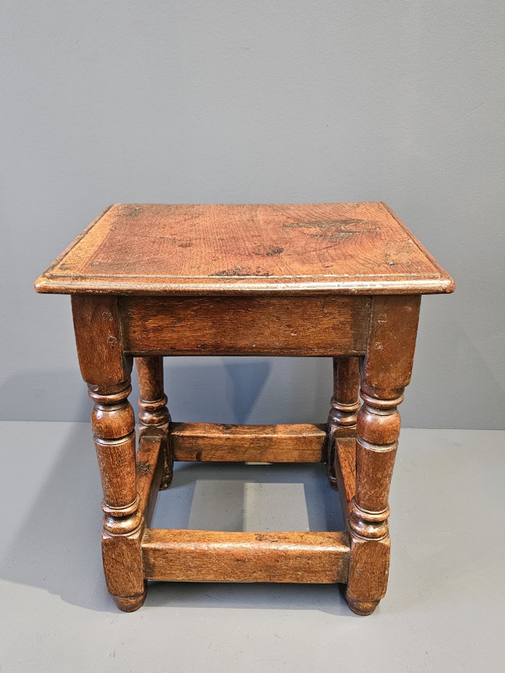 A George III oak joint stool featuring turned legs, lower stretchers, and a moulded rectangular top.