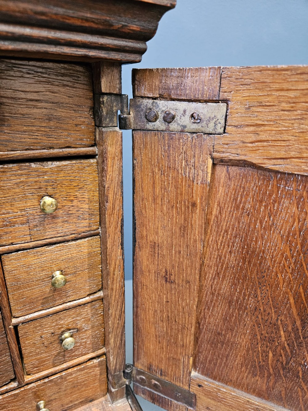 A George II dark oak spice cupboard with a moulded cornice, a single fielded-panel door, and a brass keyhole escutcheon. View II