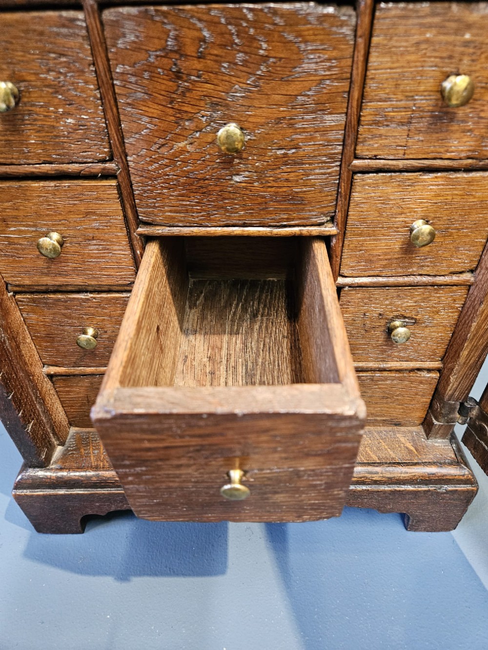 A George II dark oak spice cupboard with a moulded cornice, a single fielded-panel door, and a brass keyhole escutcheon. View IV