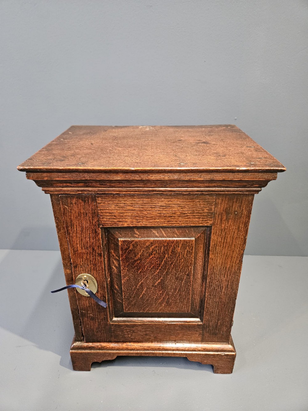 A George II dark oak spice cupboard with a moulded cornice, a single fielded-panel door, and a brass keyhole escutcheon. View VII