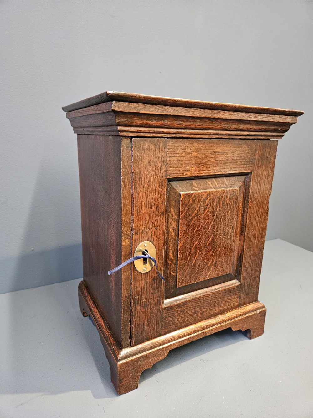 A George II dark oak spice cupboard with a moulded cornice, a single fielded-panel door, and a brass keyhole escutcheon. View VIII