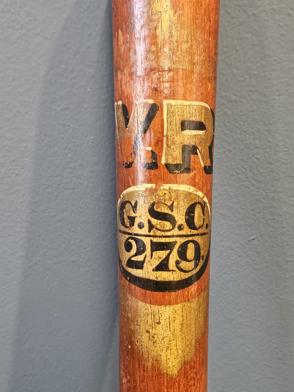 A turned Victorian mahogany police truncheon featuring a ribbed handle and painted VR royal cypher detailing on a warm brown shaft. View III