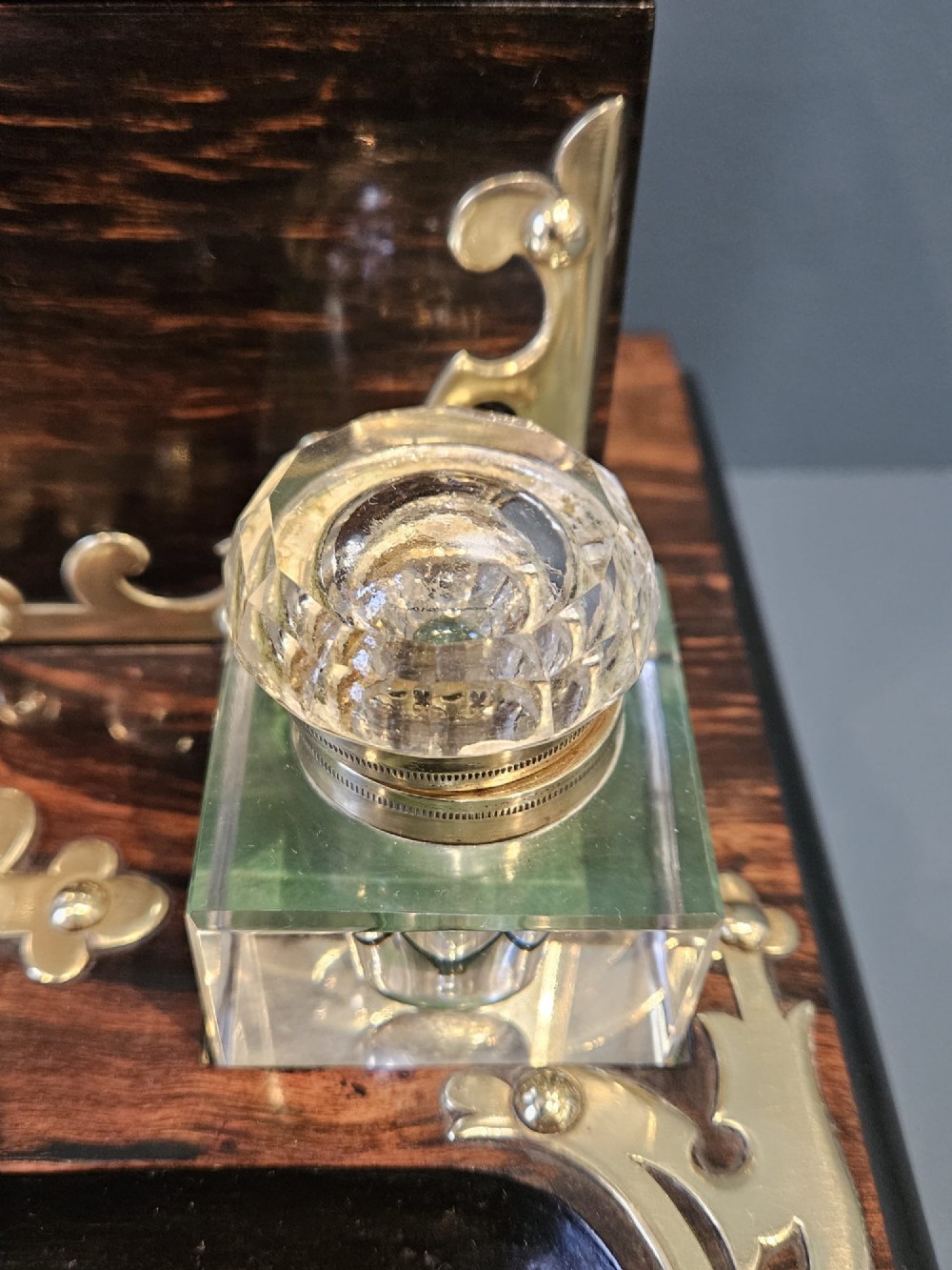 A Victorian coromandel wood stationery box and inkstand featuring gothic brass strapwork mounts, a domed lid, two glass inkwells, and a lower drawer with a key. View VI