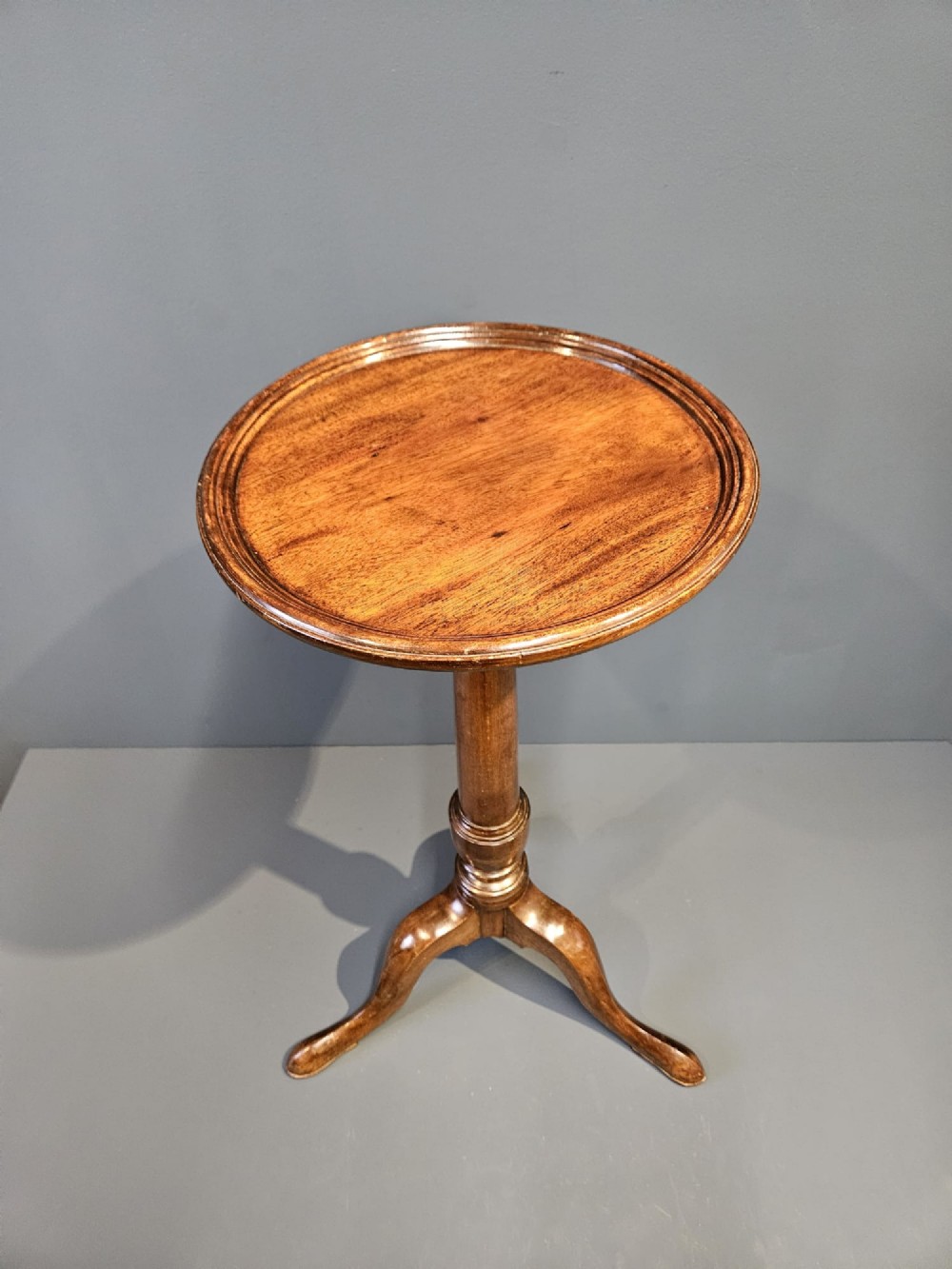 A Georgian mahogany wine table featuring a circular top with a moulded rim supported by a turned pedestal stem on tripod legs. View II